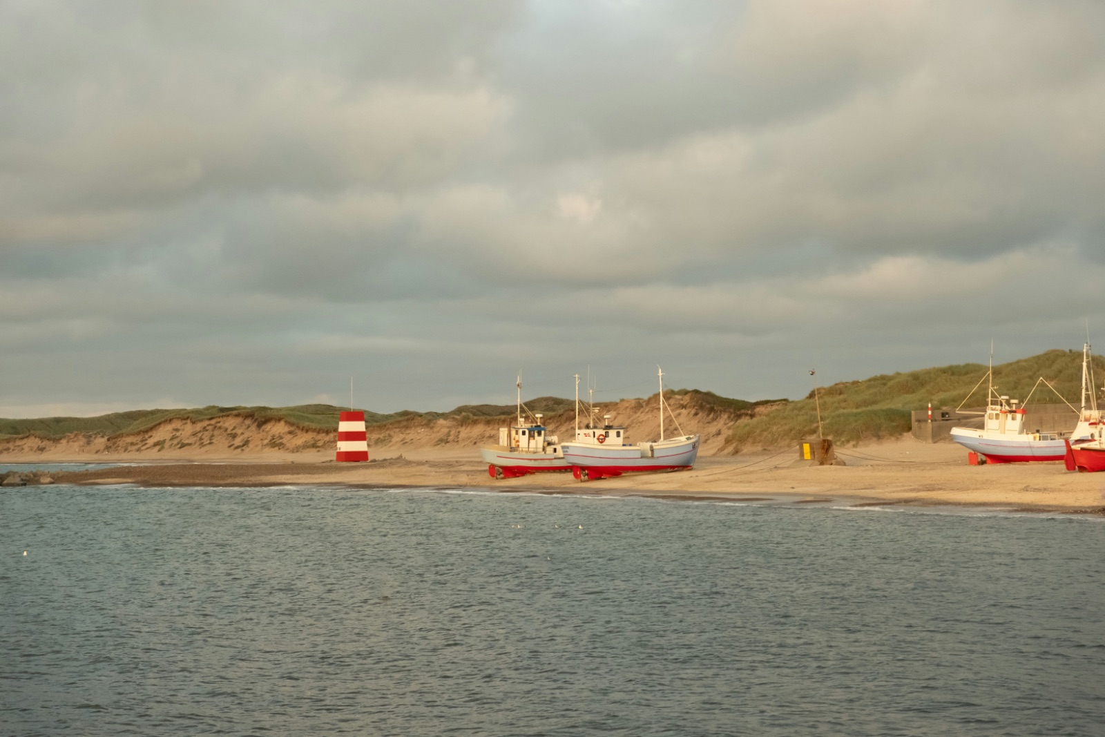 Fiskerkuttere på stranden i aftenlys
